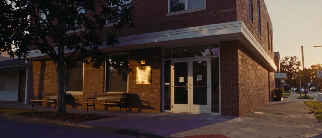 A midcentury brick office building exterior in late sun.