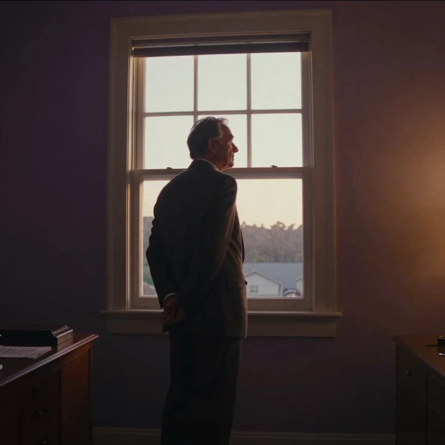 A silhouette at an office window, looking out.